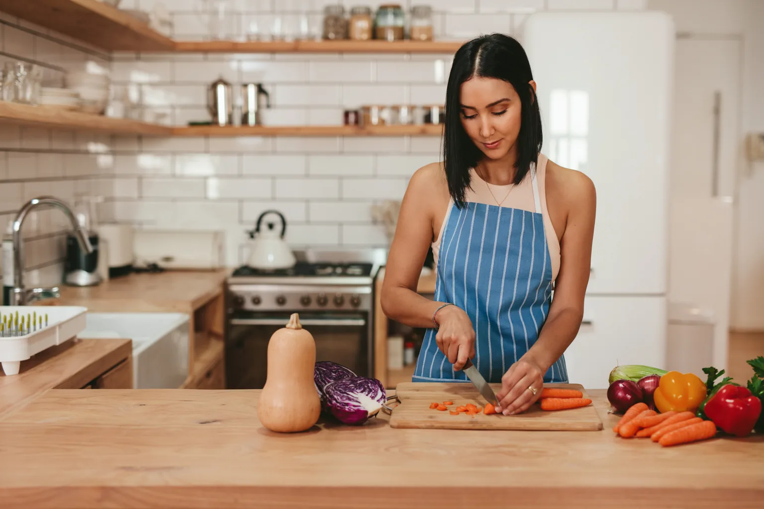 A woman preparing fresh vegetables in a home kitchen.